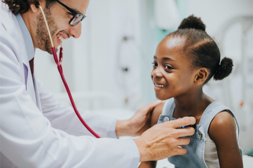 Male doctor wearing a stethescope examining a young girl