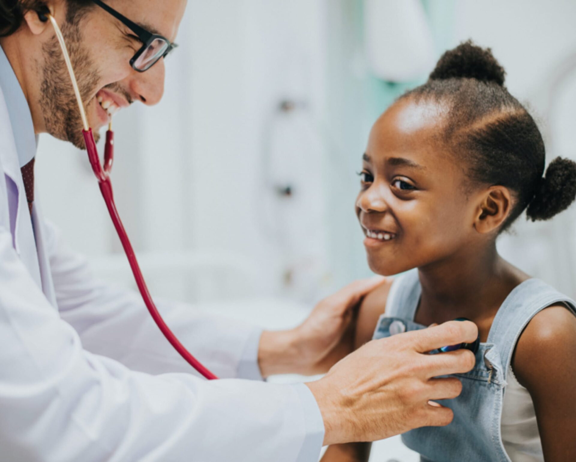 Male doctor wearing a stethescope examining a young girl