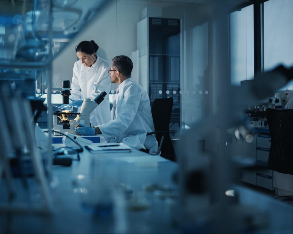 researchers in a dark room talking in front of a microscope