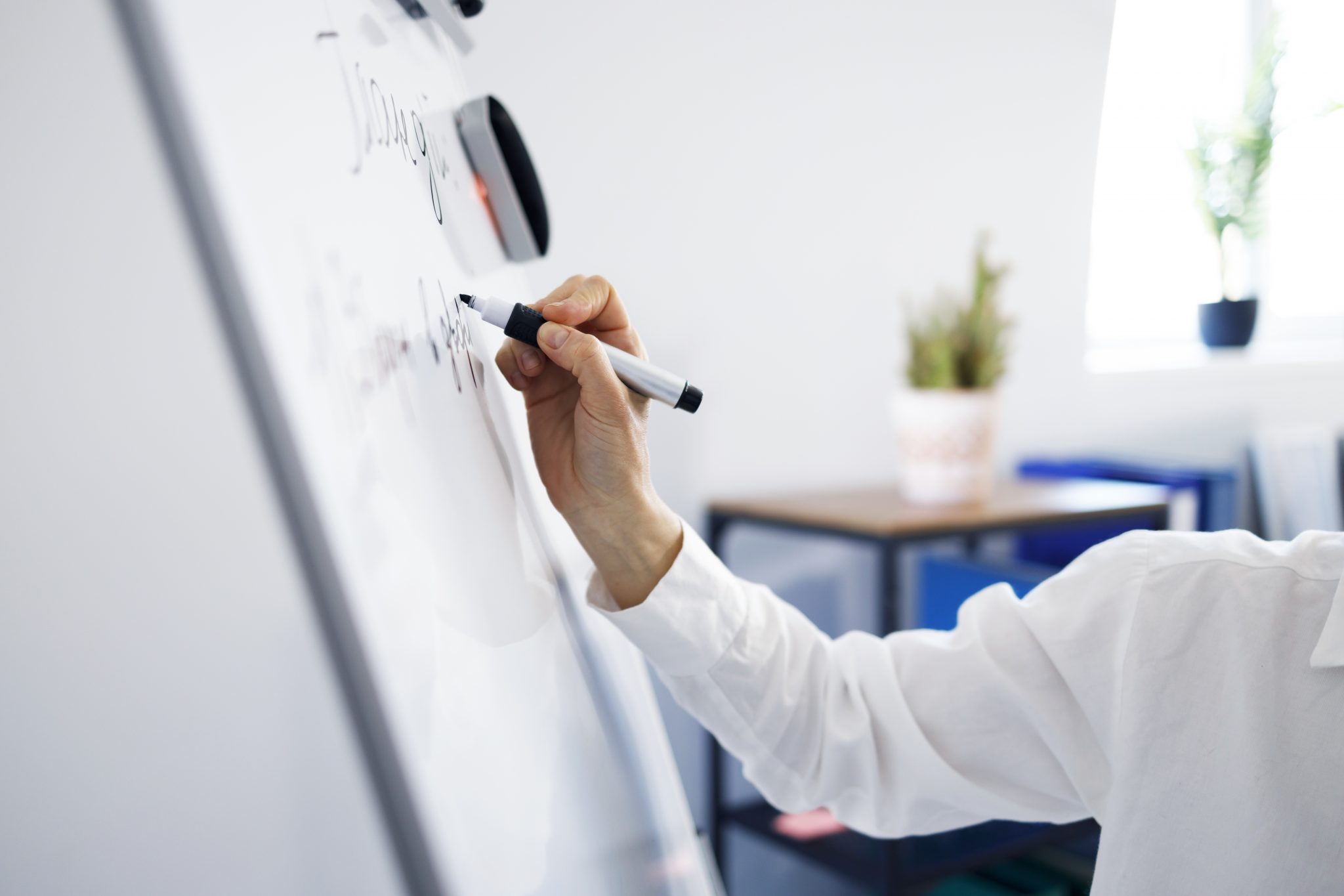 A business person holding a dry erase marker to a white board